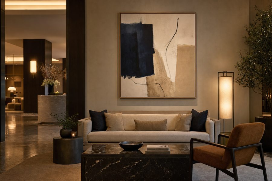 A large framed artwork installed above a hotel lobby lounge sofa